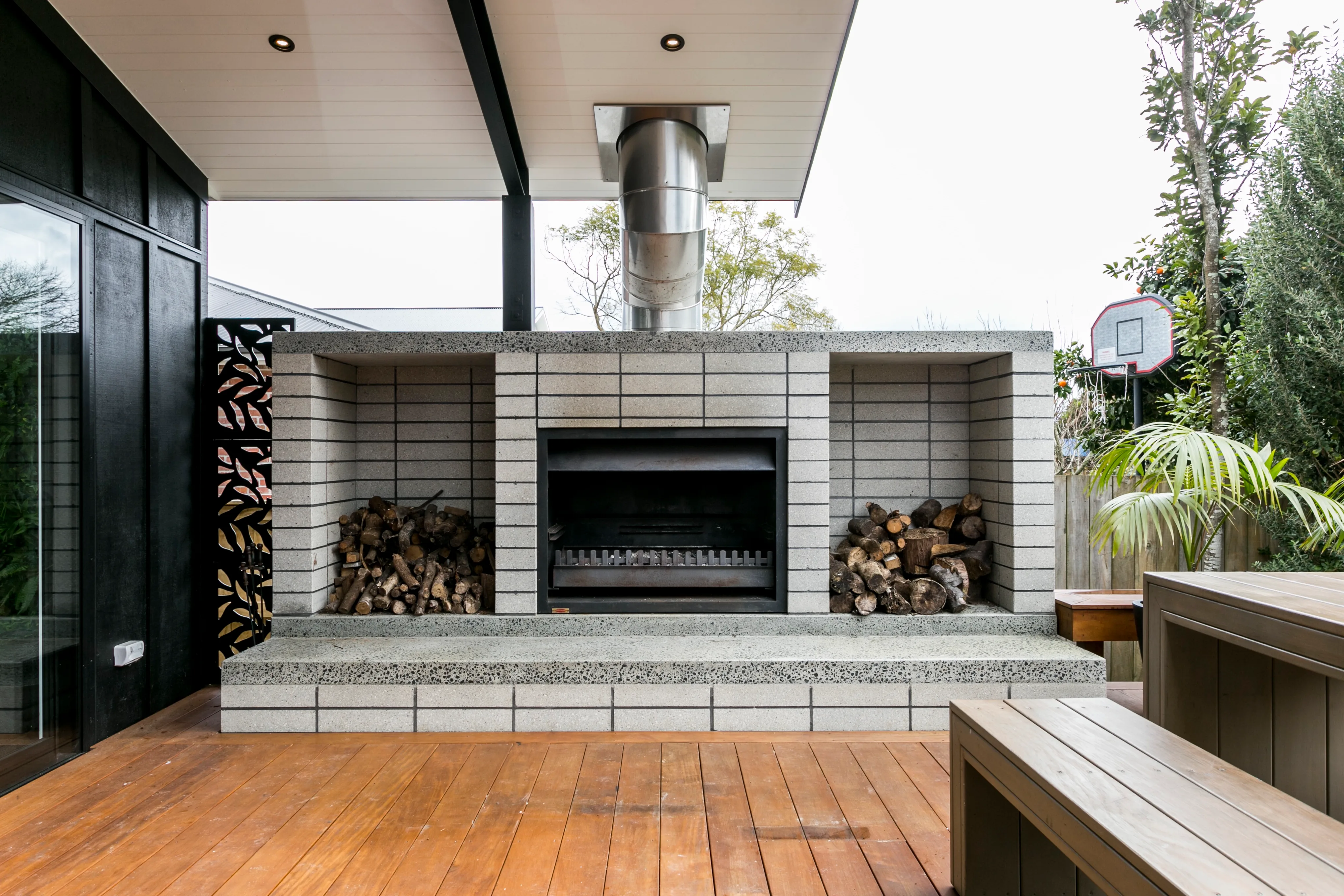 Hazelmere house – outdoor fireplace with built-in firewood storage on the covered deck