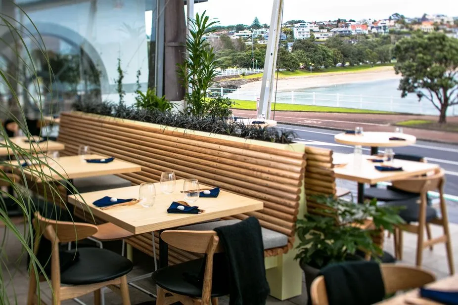 True Food and Yoga – outdoor dining tables on the deck overlooking the beach and harbour