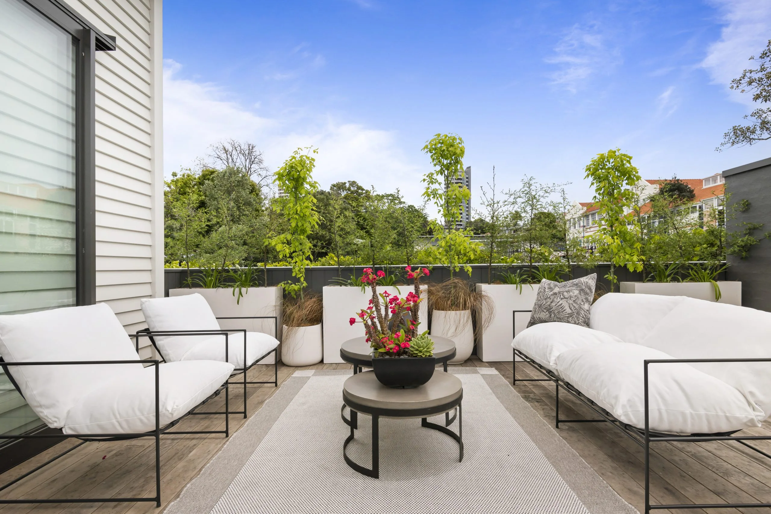 Curran – rooftop deck lounge area framed by planter boxes, with the city skyline beyond