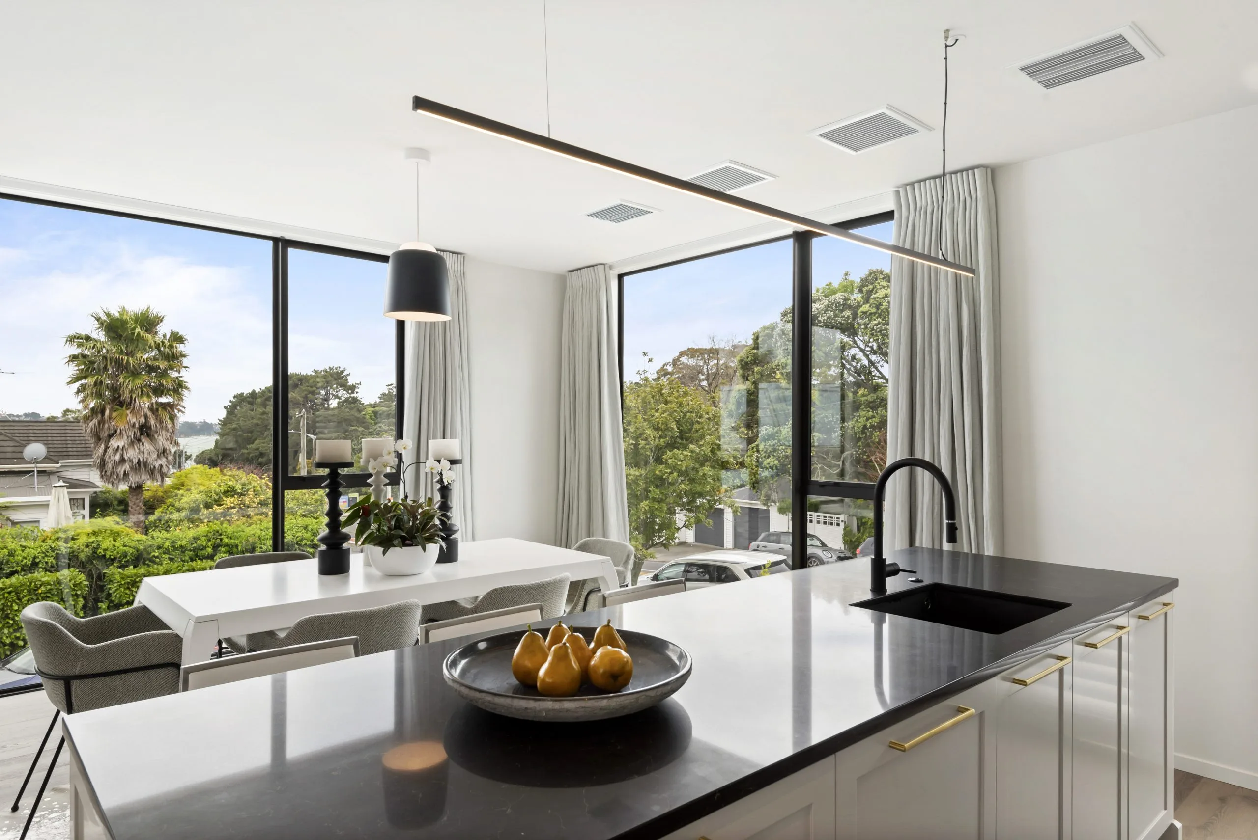 Curran – kitchen island looking through to the dining table, with harbour views through floor-to-ceiling glazing