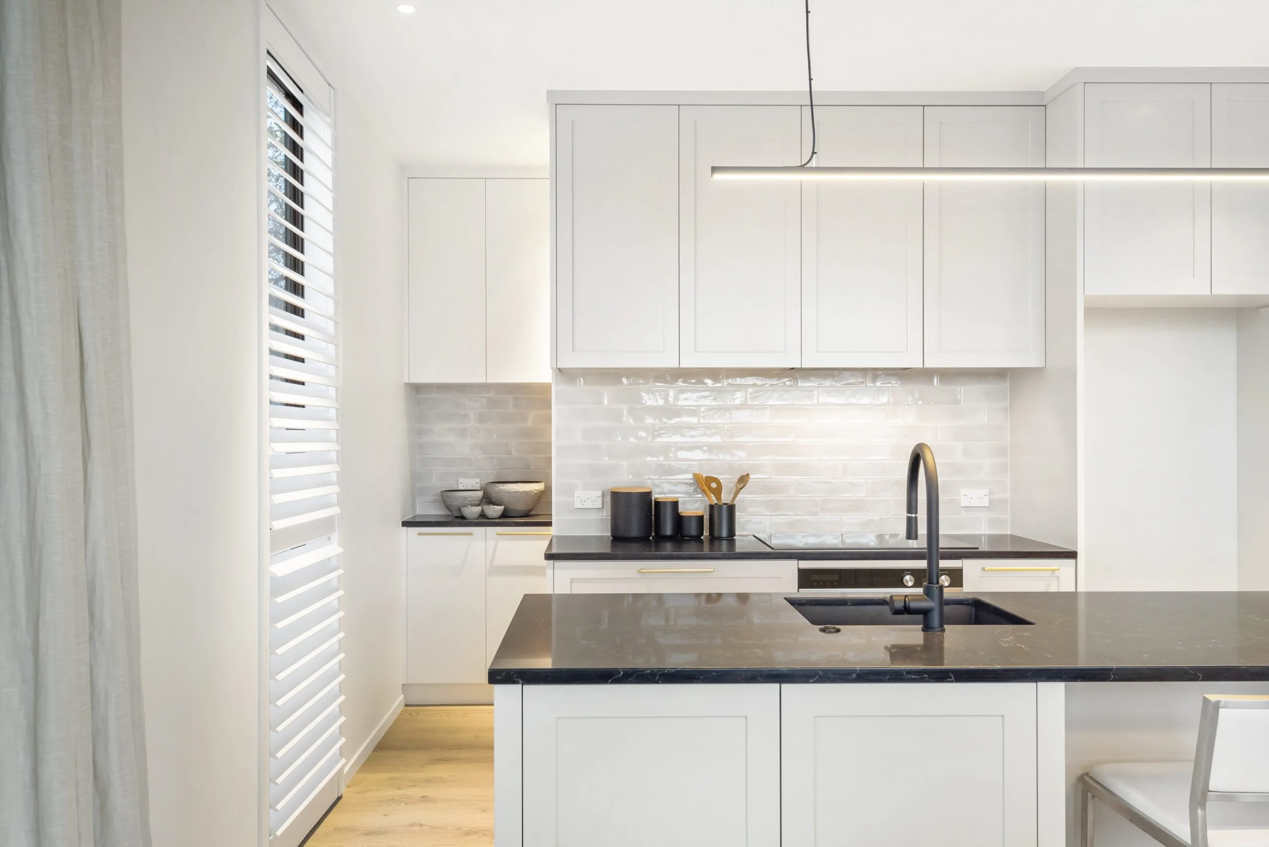 Curran – kitchen detail with black stone benchtop, tiled splashback and matte black tapware