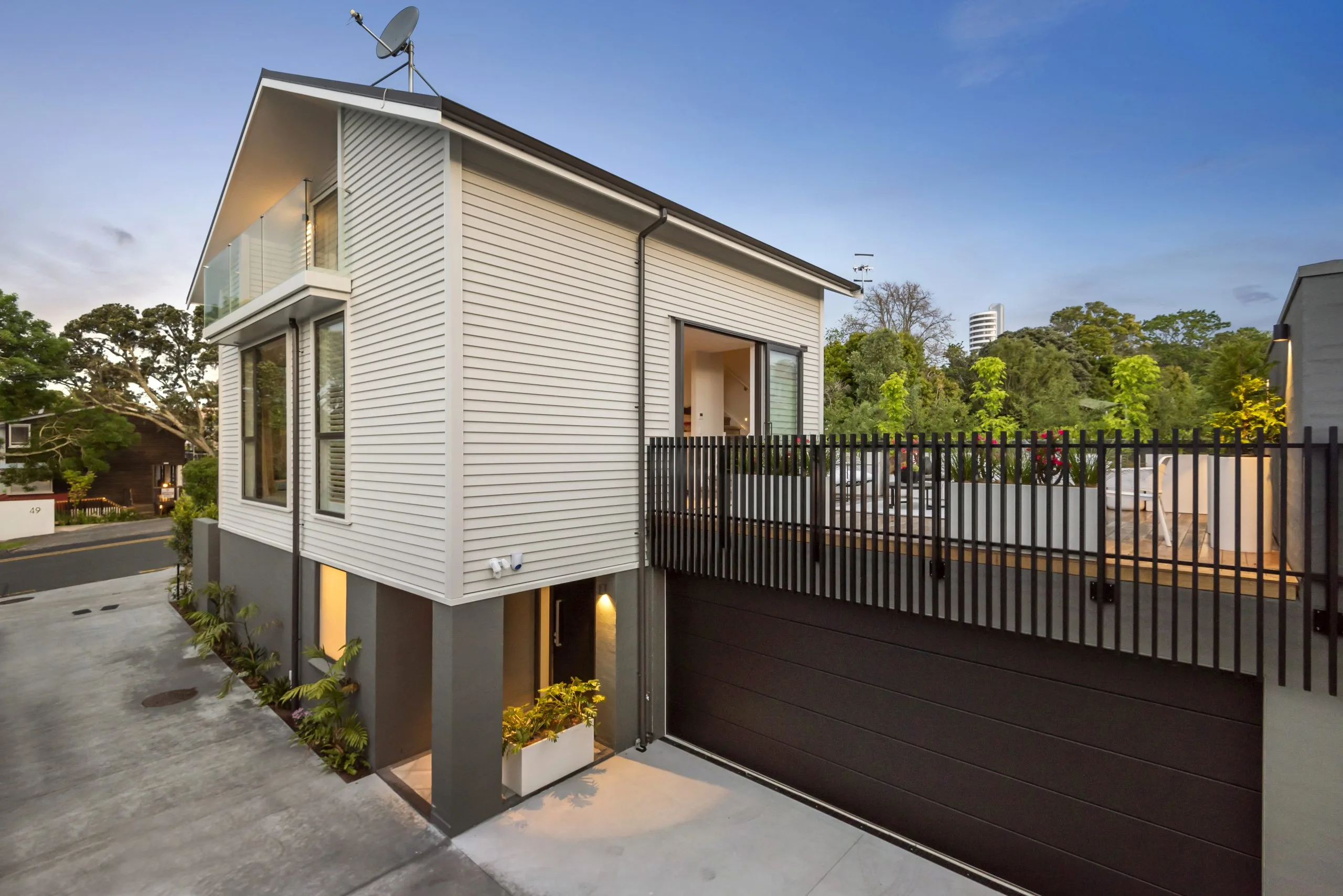Curran – street elevation at dusk, weatherboard cladding over a dark base with garage