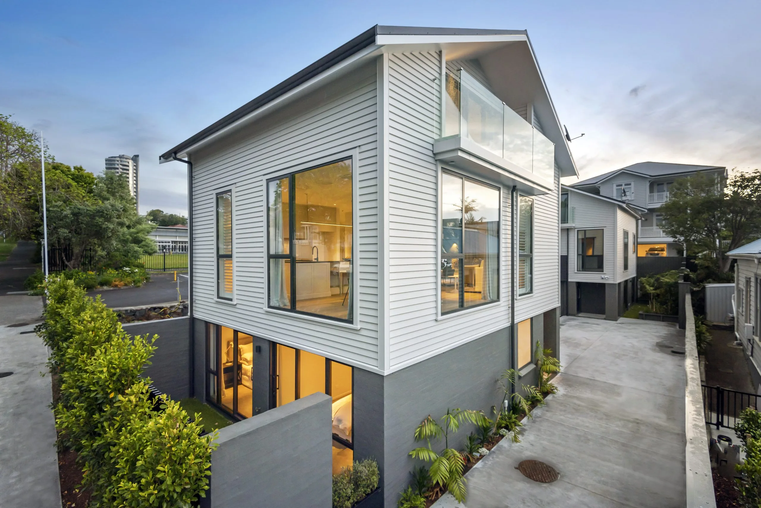 Curran – exterior corner glazing lit up at dusk, overlooking neighbouring villas