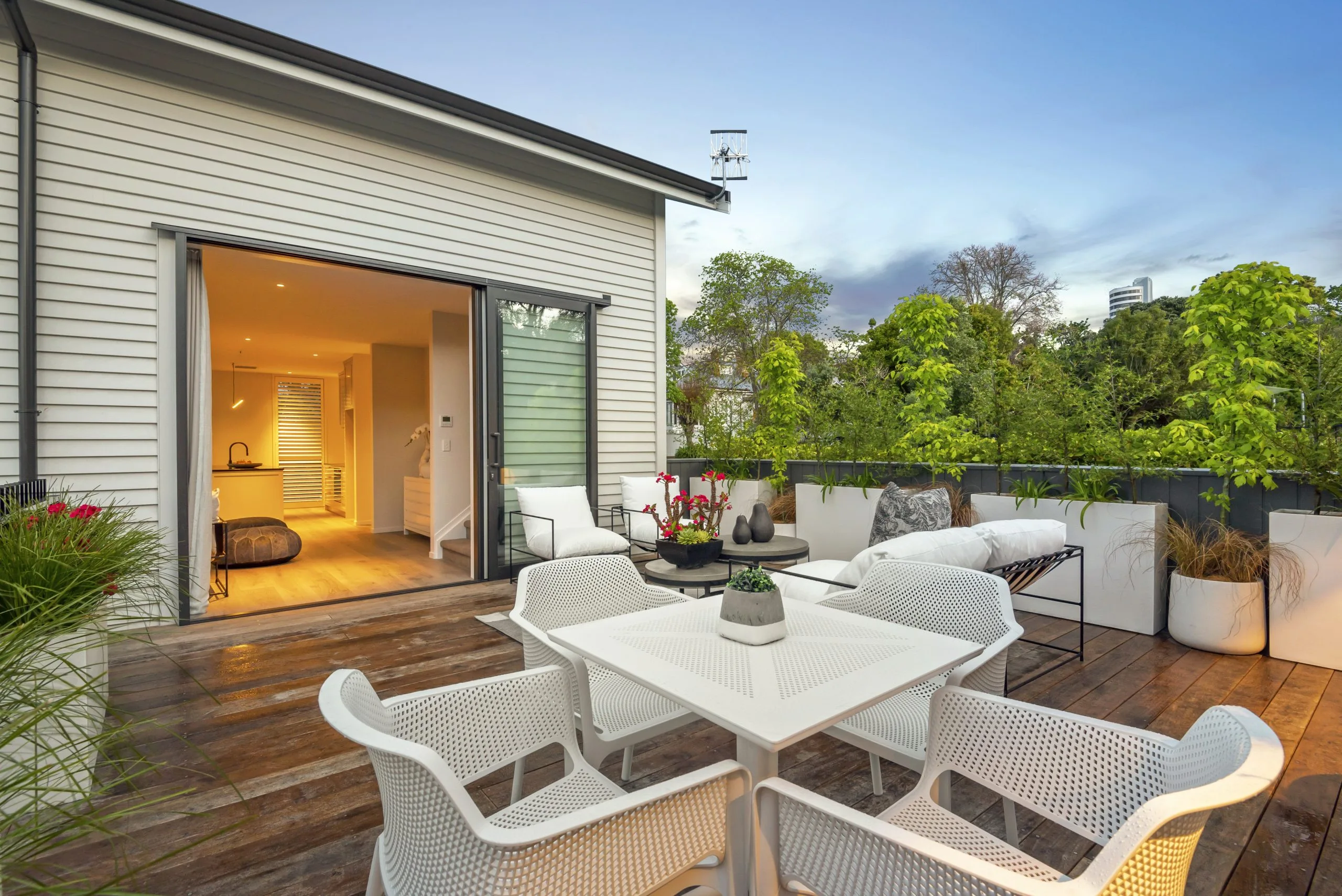 Curran – rooftop deck dining table with the kitchen glowing through open doors at dusk