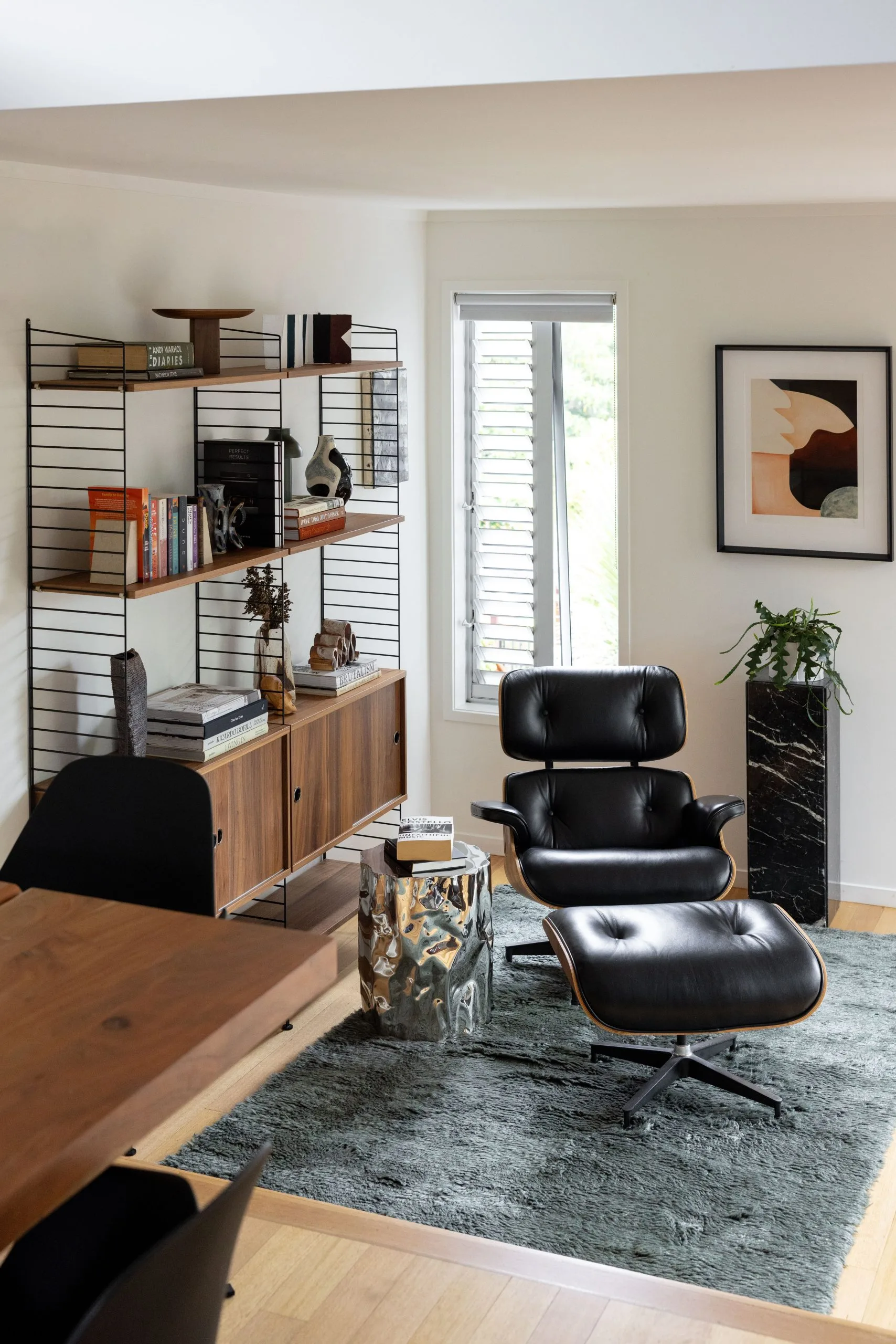 Deep Creek – reading nook with a black leather lounge chair, shelving and a marble side table