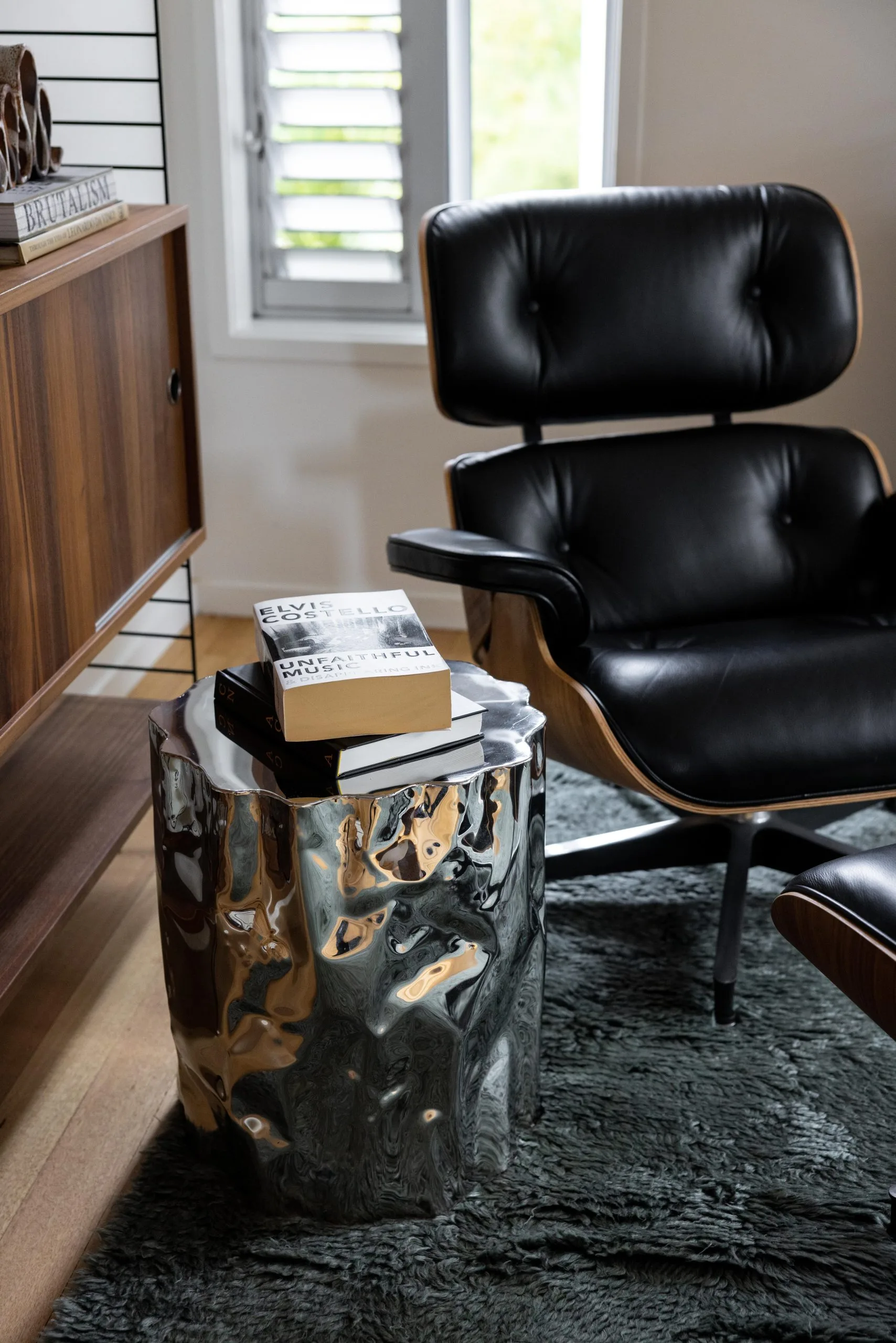 Deep Creek – mirrored side table with books beside the black leather lounge chair