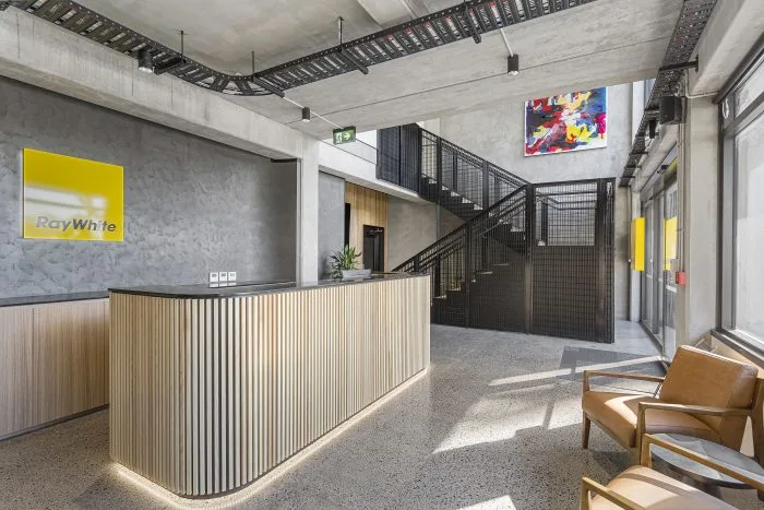 Ray White Manukau – reception desk and waiting area, with staircase and street view beyond