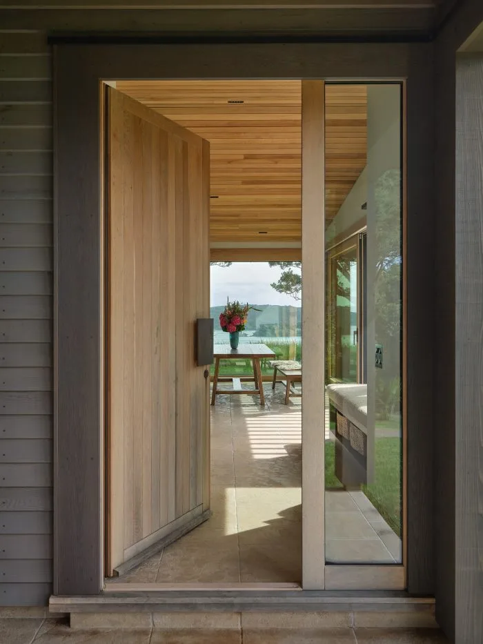 Waiheke Cabin – front door open to the dining table, with Hauraki Gulf views beyond